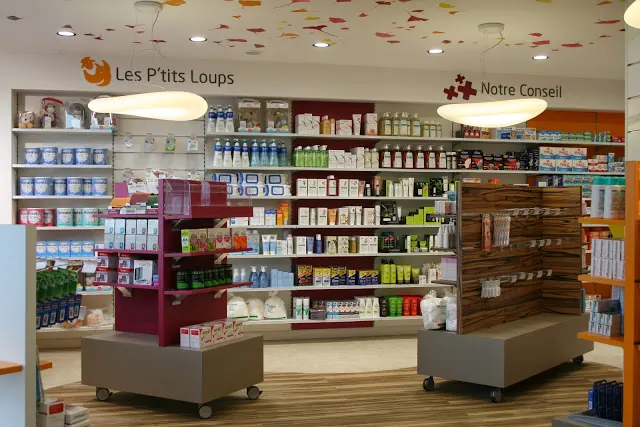 L'intérieur d'une pharmacie, rayonnages éclairés et plafond à spots