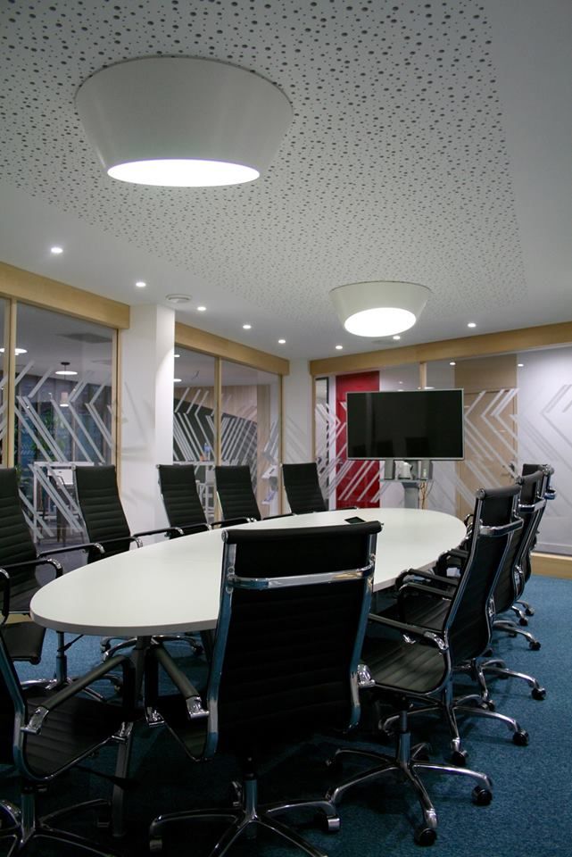 Salle de réunion avec grande table ovale et plafonniers circulaires