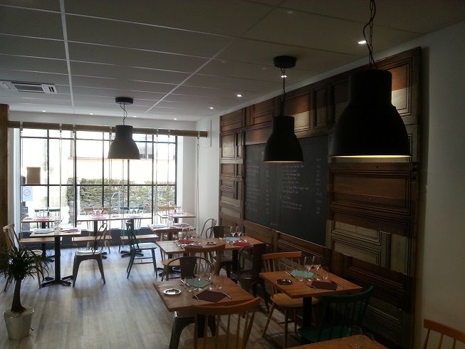 Salle de restaurant éclairée par de grandes suspensions noires